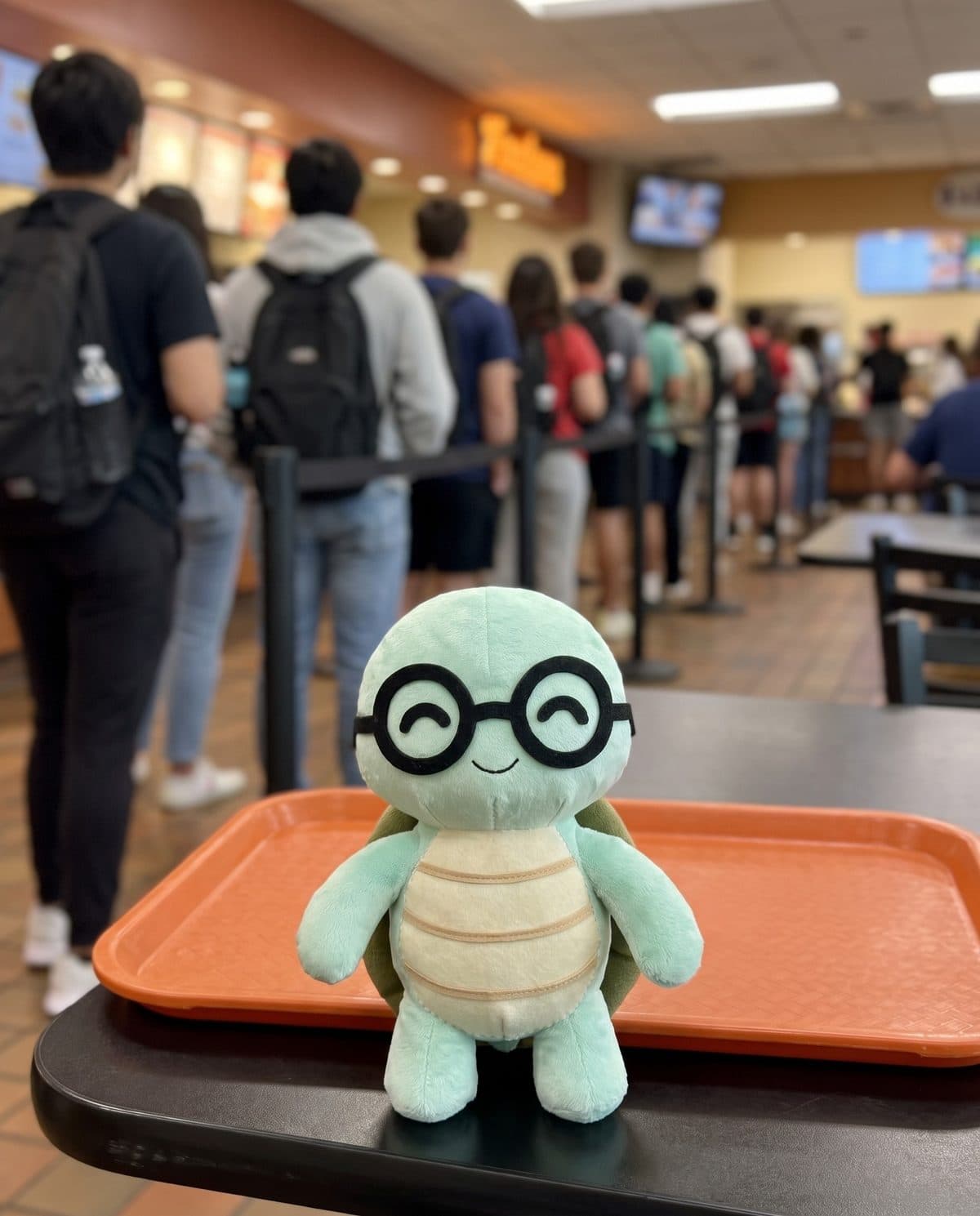 The NoTestudo turtle on a lunch tray at a busy campus food court.